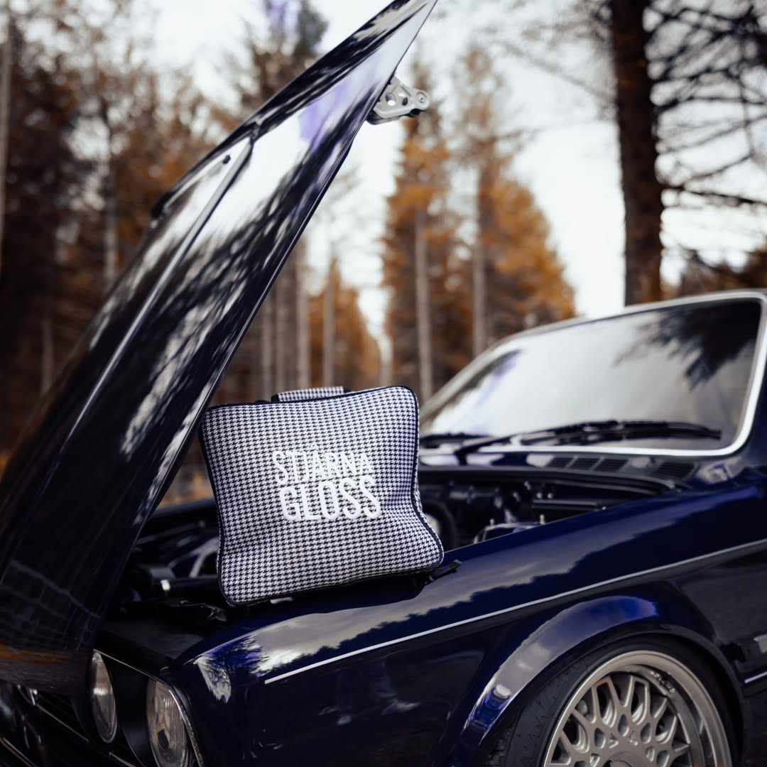 Black and white checkered bag with 'Bella' branding on a car hood outdoors.