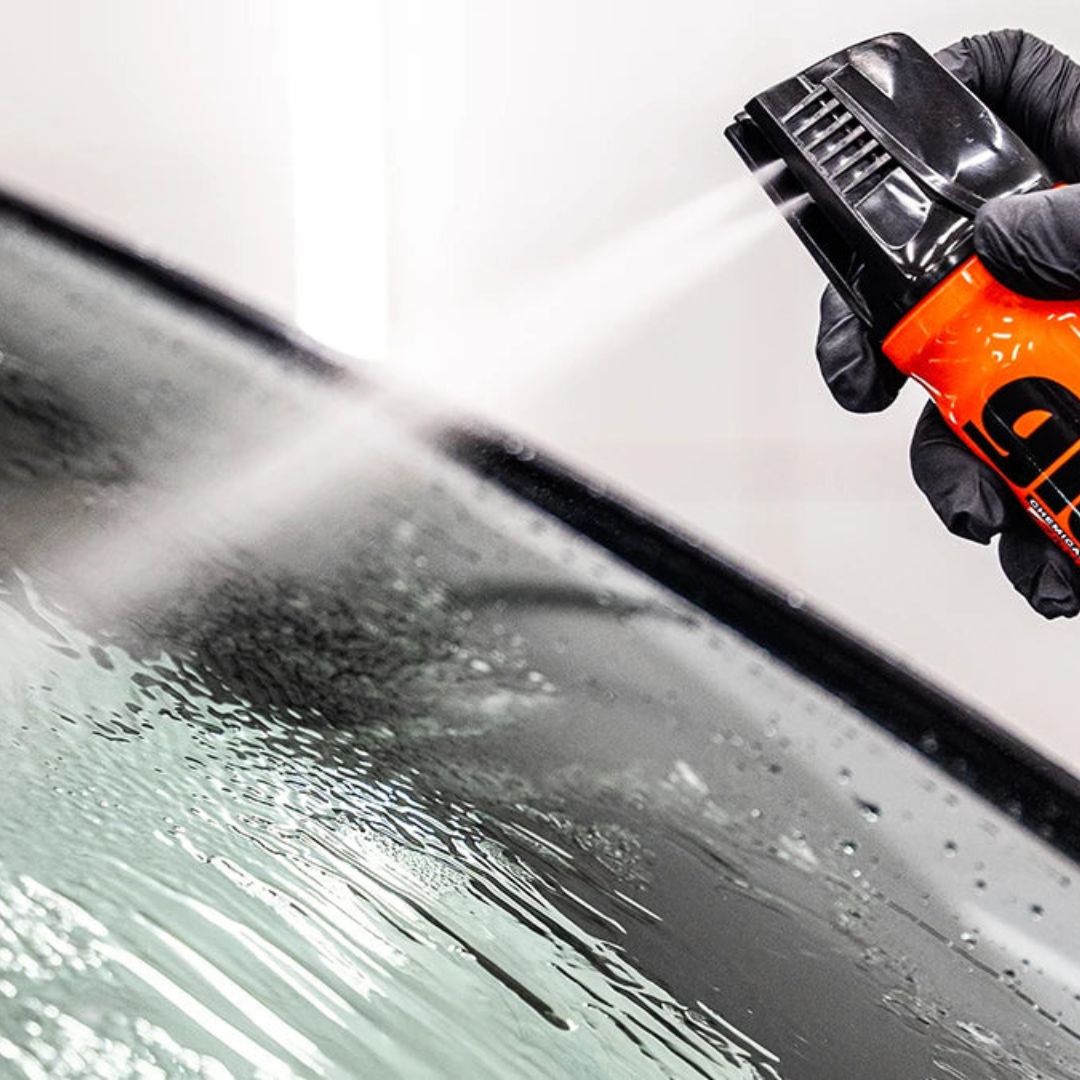 Person cleaning a car window with a high-pressure washer