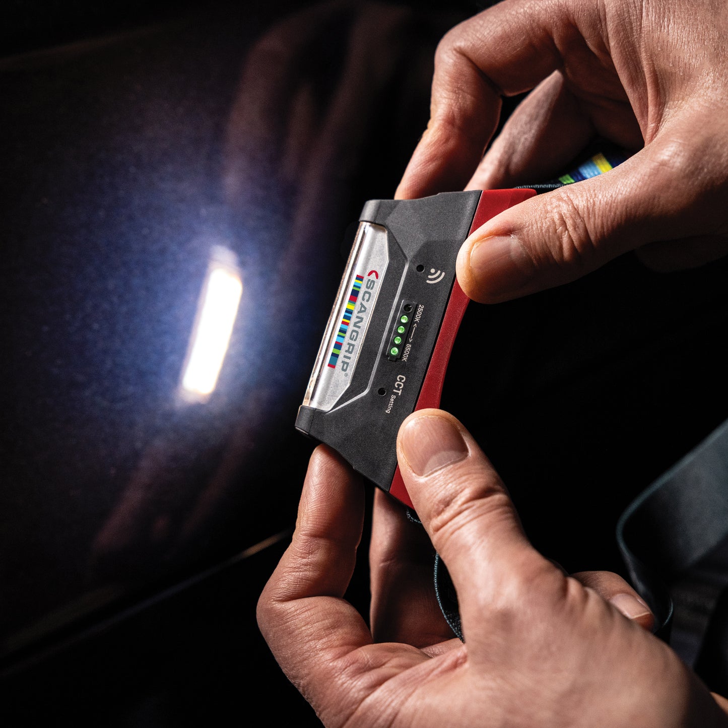 Scangrip I-Match 4 Person holding a diagnostic tool against a car's engine cover