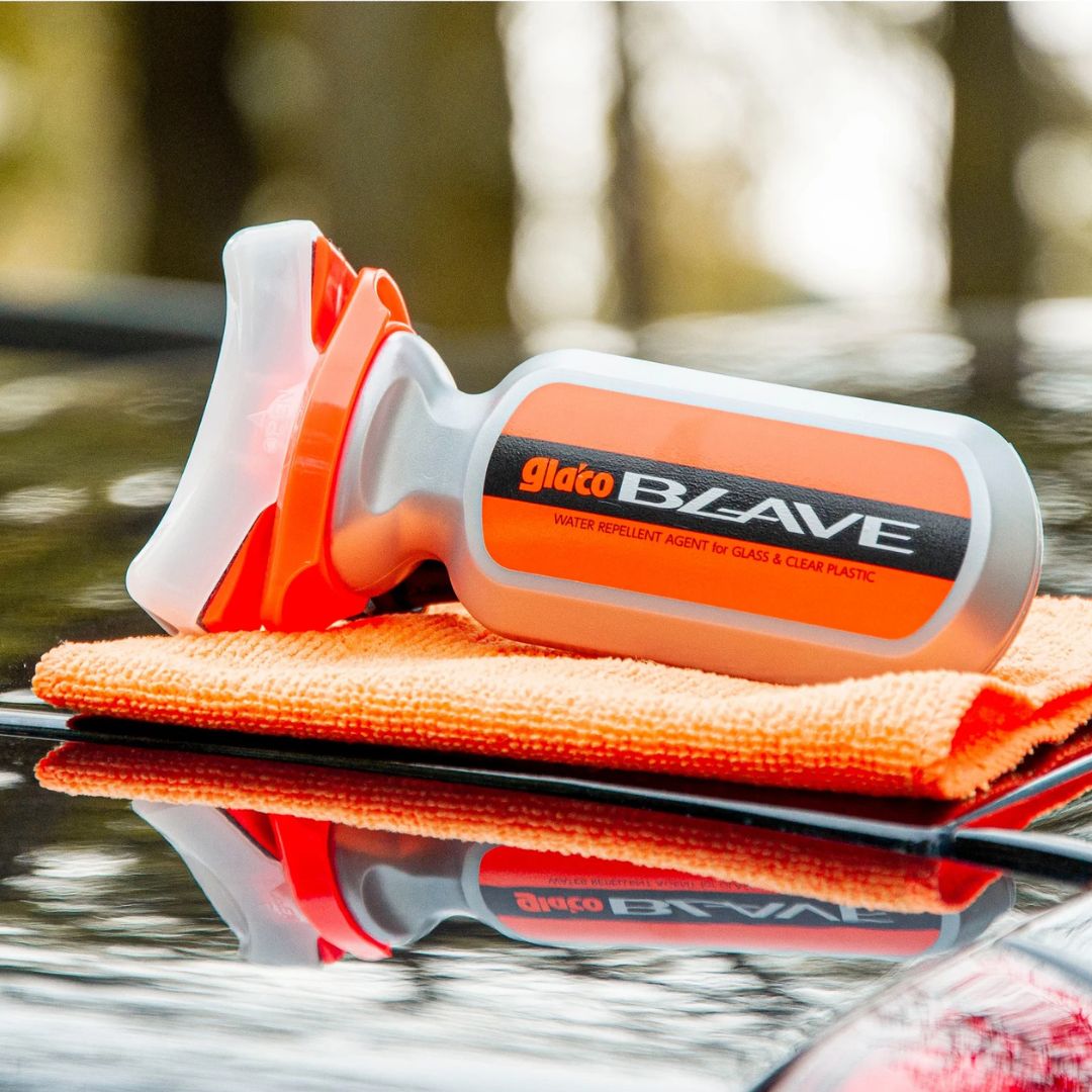 Soft99 Glaco Blave - Glass & Plastic Water Repellent 70ml car care product with orange microfiber cloth on a reflective surface.