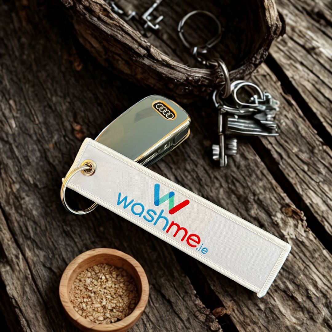 Keychain with 'washme.ie' logo on a wooden surface