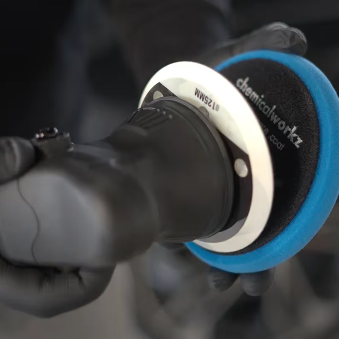 Person using a chemicalworkz DA9 polisher with a blue pad labeled 'chemicalworkz' on a dark background