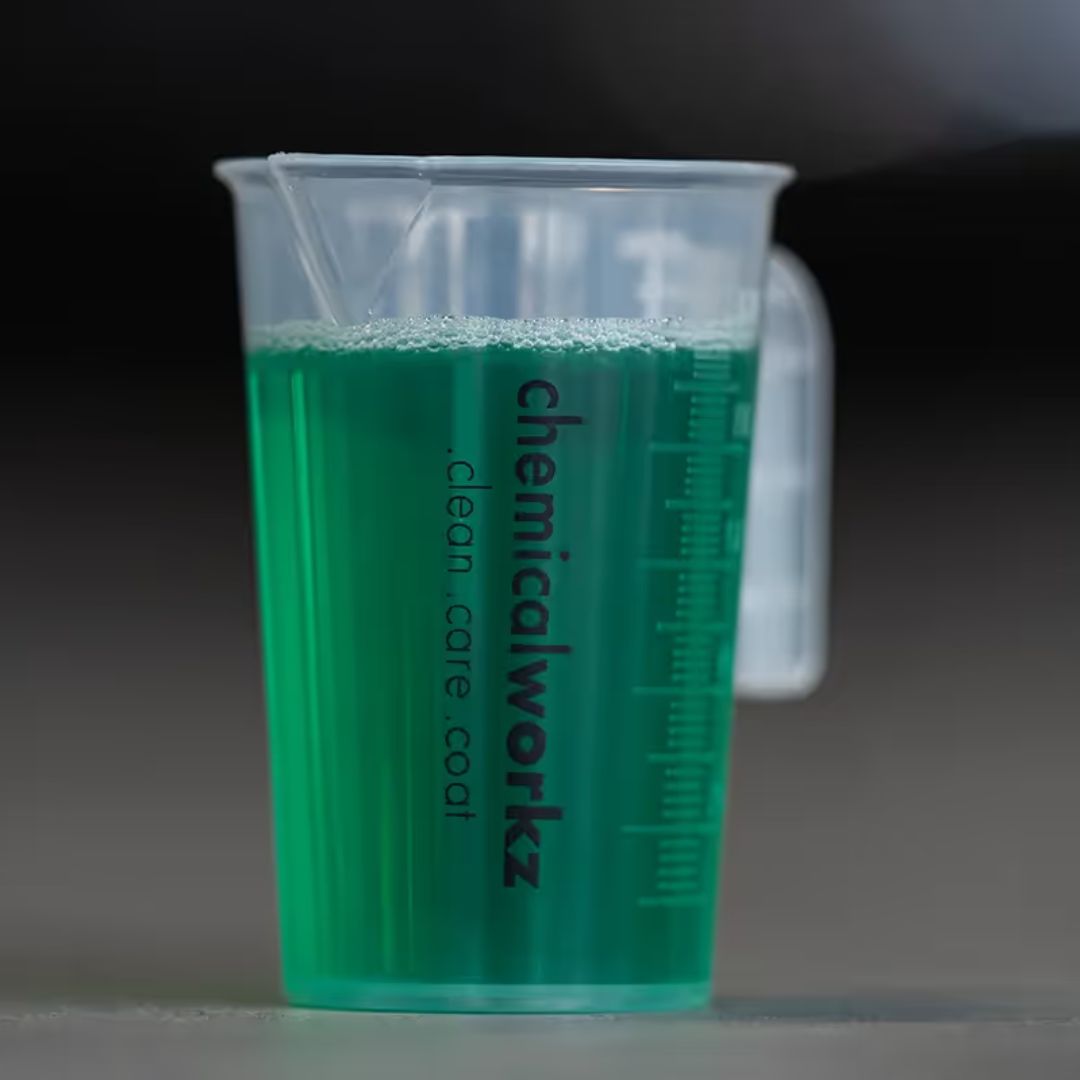 Clear plastic measuring cup with green liquid and 'chemicalworkz' branding on a dark background
