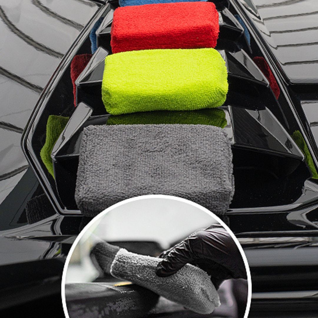 Set of colorful microfiber cloths in a car's headlight tray with a close-up of a hand using a gray cloth.