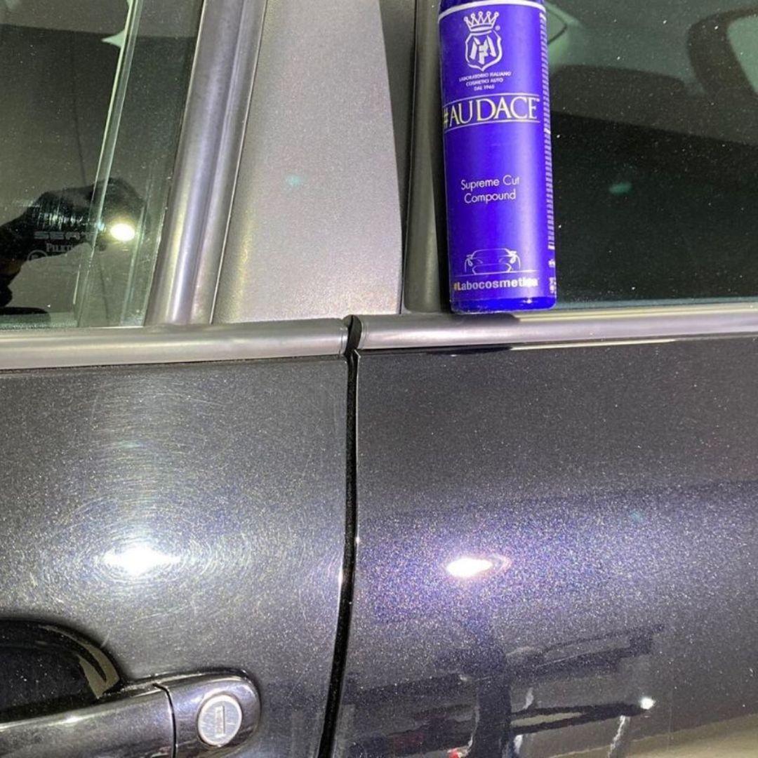 Blue bottle of Labocosmetica 'Audace' heavy cut compound on a car door showing before and after polishing