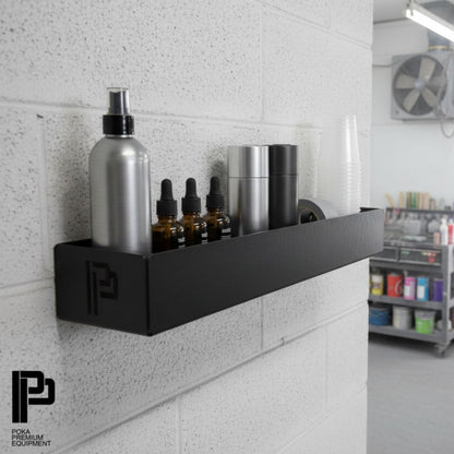 Black shelf with polishing compounds products on a tiled wall in a workshop setting.