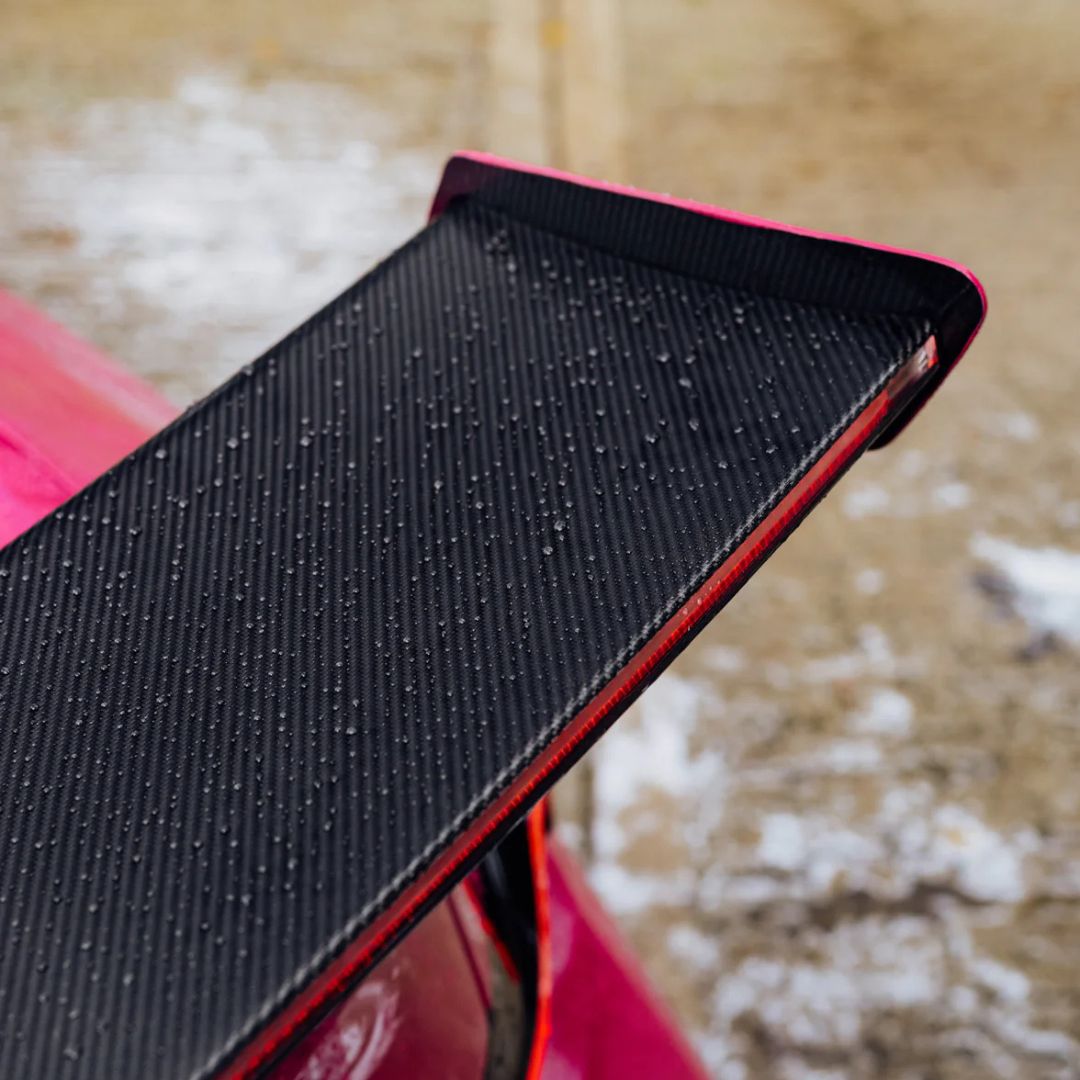 Black textured car spoiler on a red car with water beading from Stjarnagloss Glatt