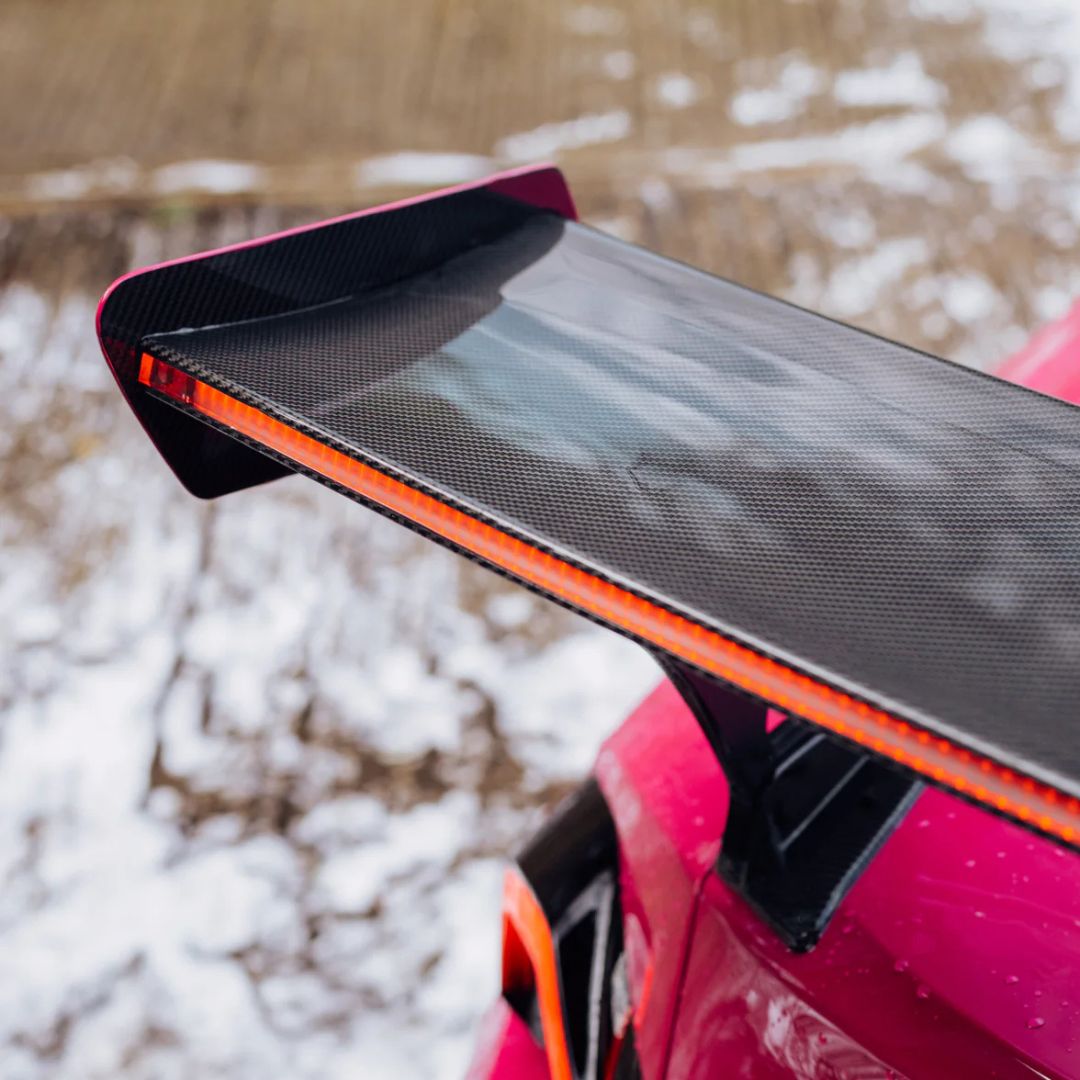 Car spoiler with carbon fiber texture on a pink car in a snowy landscape