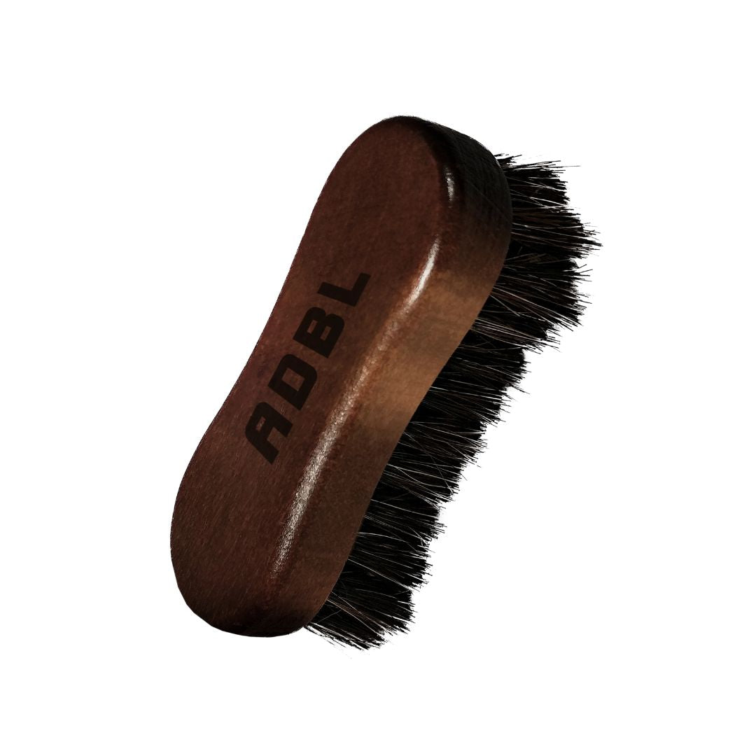Brown leather brush with black bristles and 'ADBL' branding on a white background.