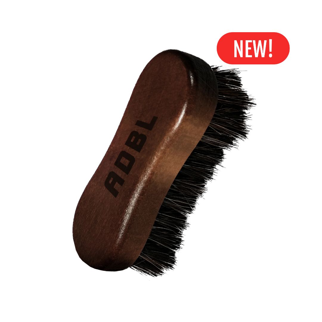 Brown leather brush with black bristles and 'ADBL' branding on a white background.