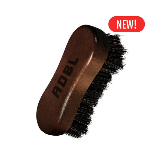 Brown leather brush with black bristles and 'ADBL' branding on a white background.