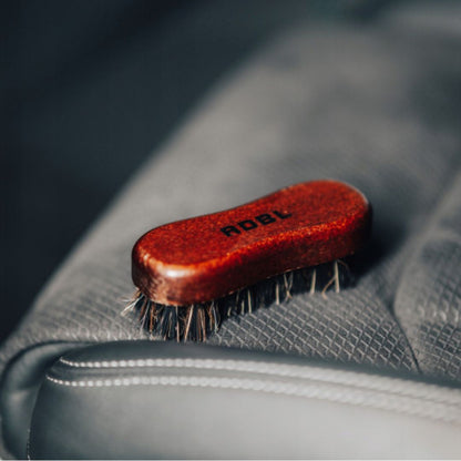 Brown ADBL Leather Brush with bristles on a alcantara seat