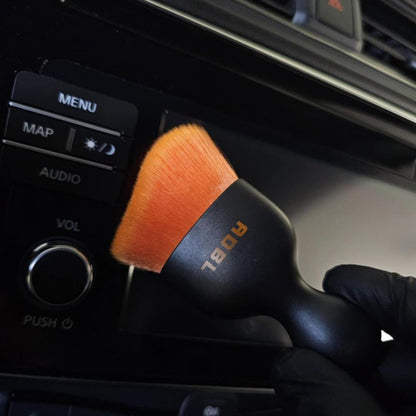 ADBL Smooth Operator Ultra Soft Interior Brush Car interior cleaning brush with orange bristles being used on a car dashboard.