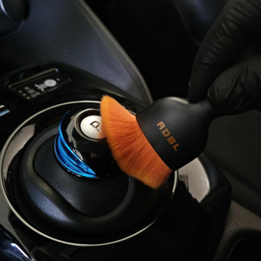 ADBL Smooth Operator Ultra Soft Interior Brush Car interior cleaning brush with orange bristles being used on a car gear shift.