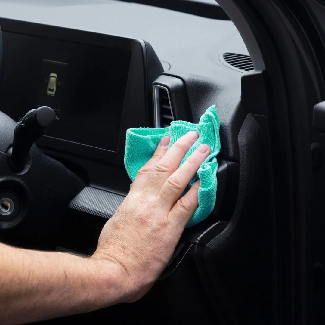 Hand cleaning car interior with a green microfibre Autoglym All Purpose Cloth 360gsm