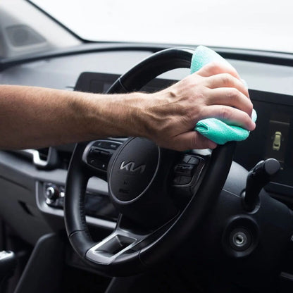 Person cleaning a car steering wheel with a green Autoglym All Purpose Cloth 360gsm