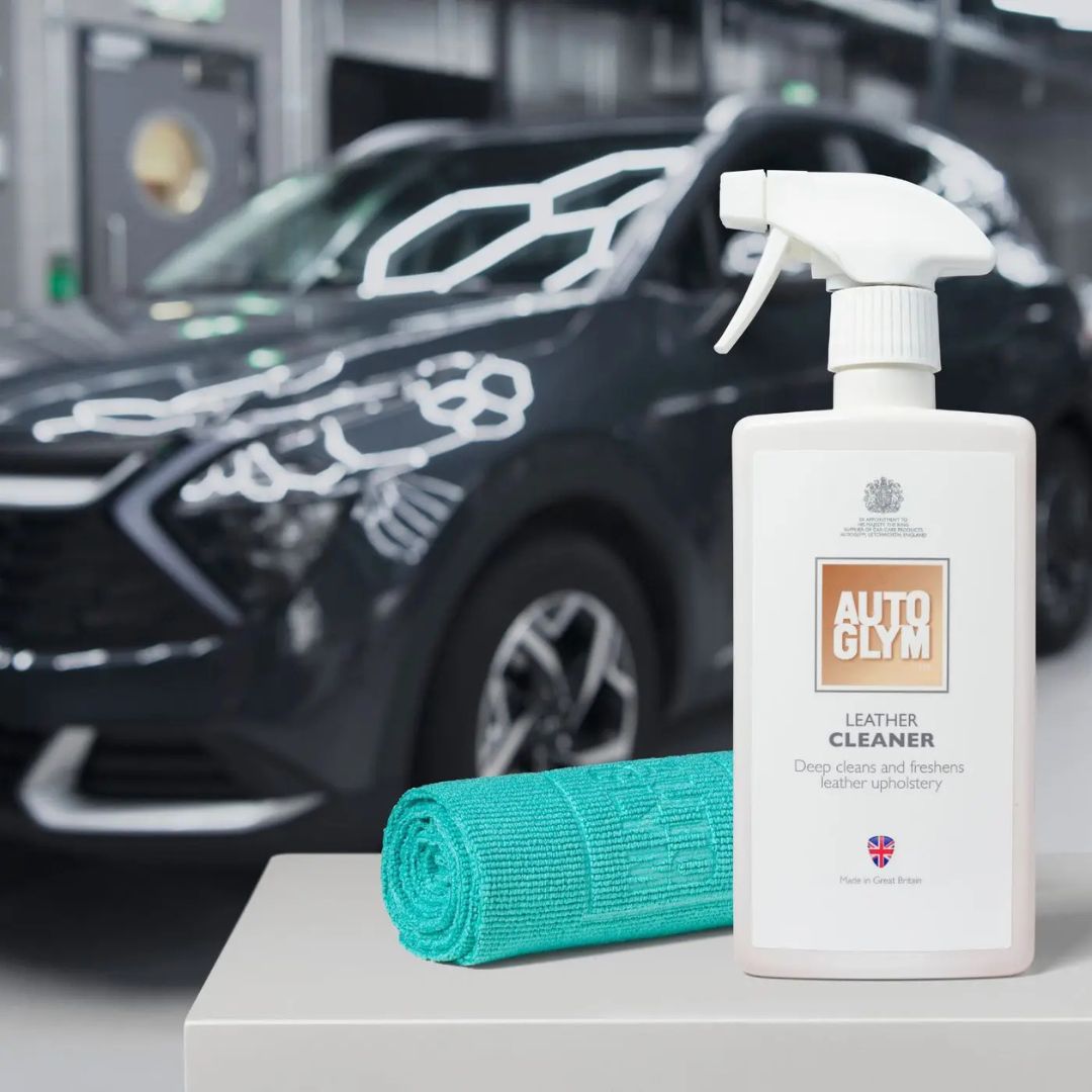 Autoglym leather cleaner bottle with a green Autoglym All Purpose Cloth 360gsm towel in front of a car.