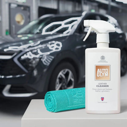 Autoglym leather cleaner bottle with a green Autoglym All Purpose Cloth 360gsm towel in front of a car.