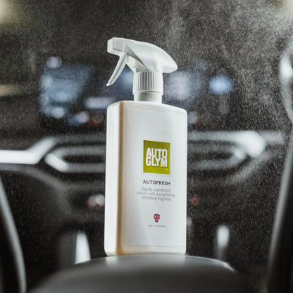 Spray bottle labeled 'Autoglym Autofresh' being used on a car interior.