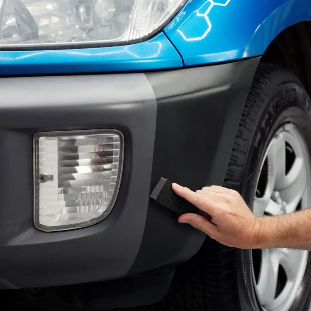 Person applying Autoglym Trim restorer to strip to a car's headlight cover