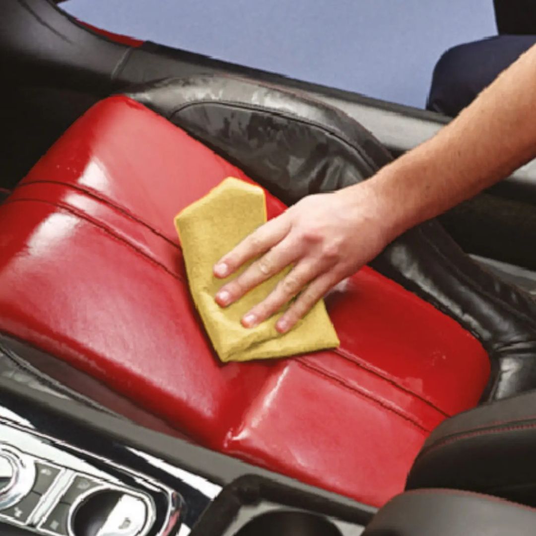 Person cleaning a car seat with a yellow cloth