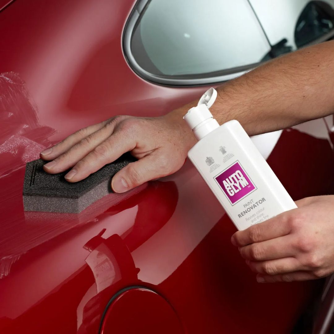Person applying a car polish product to a red car
