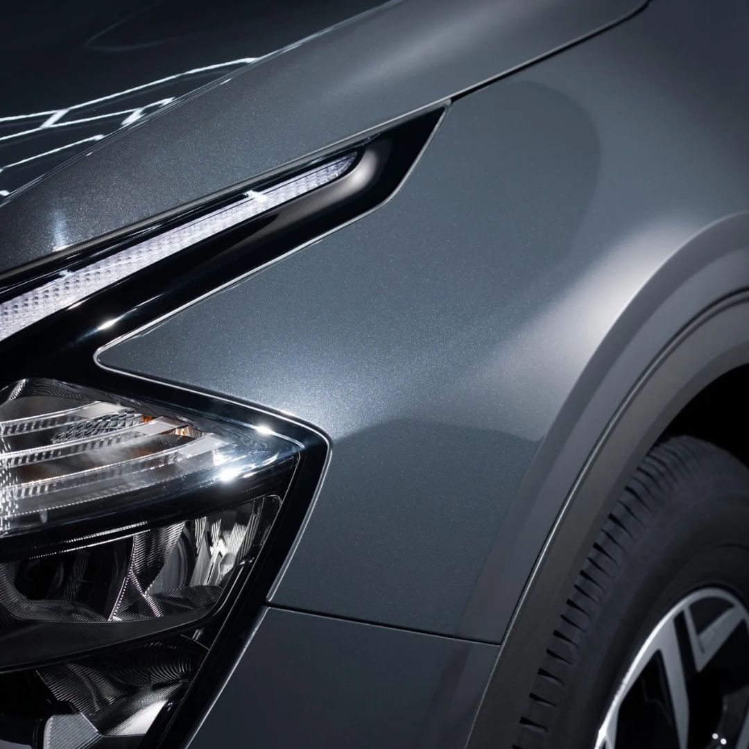 Close-up of a car's headlight and front bumper on a dark background.