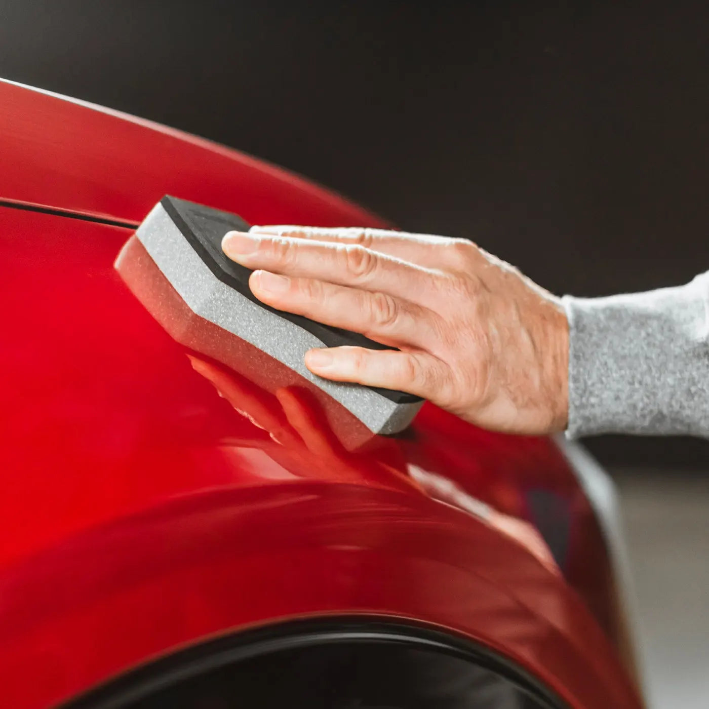 Person using a grey Autoglym Applicator on a red car surface