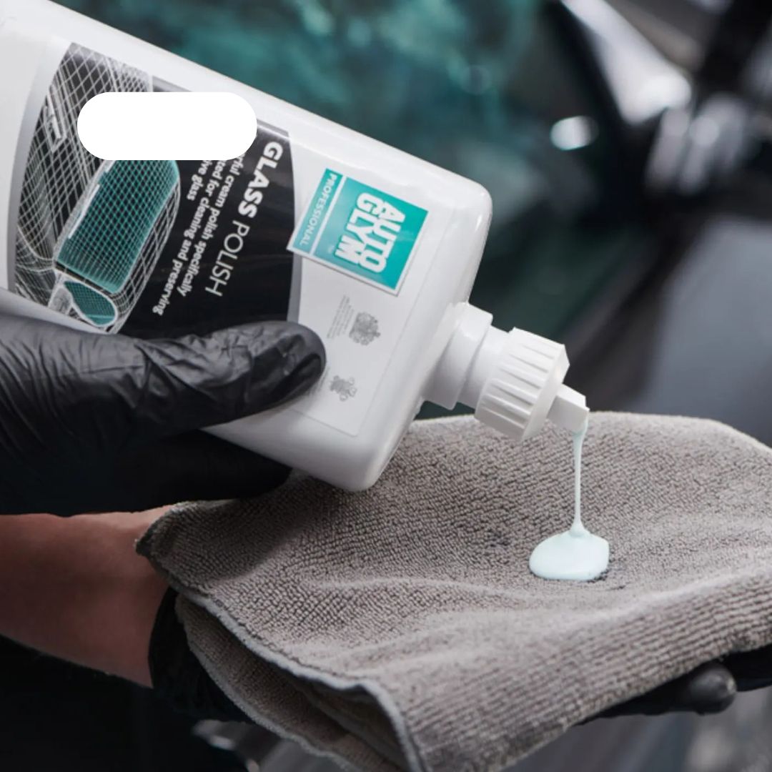 Hand applying glass polish to a towel with a car in the background