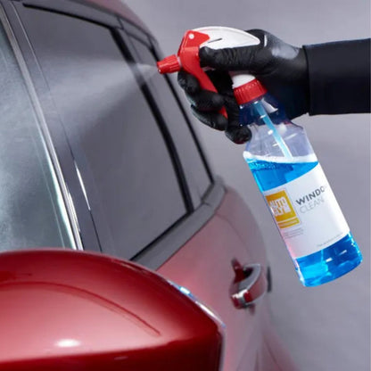 Person cleaning a car window with a spray bottle labeled 'Window Cleaner'.