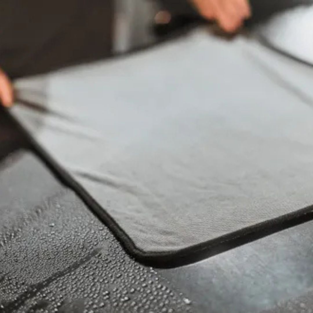 Person holding an Autloglym Drying Towel car bonnet with water droplets on a car bonnet