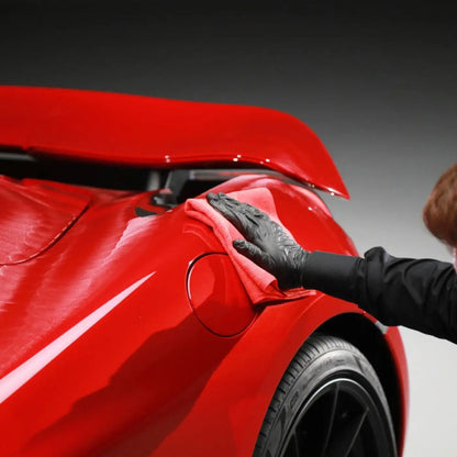 Person applying a car wrap to a red vehicle with a gray background