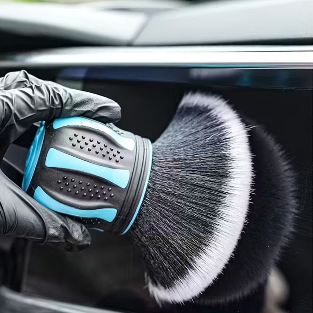 Car detailing brush with a gloved hand cleaning a car window.