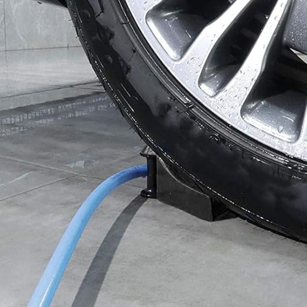 Car tire with a hose glider and blue hose on a concrete floor.