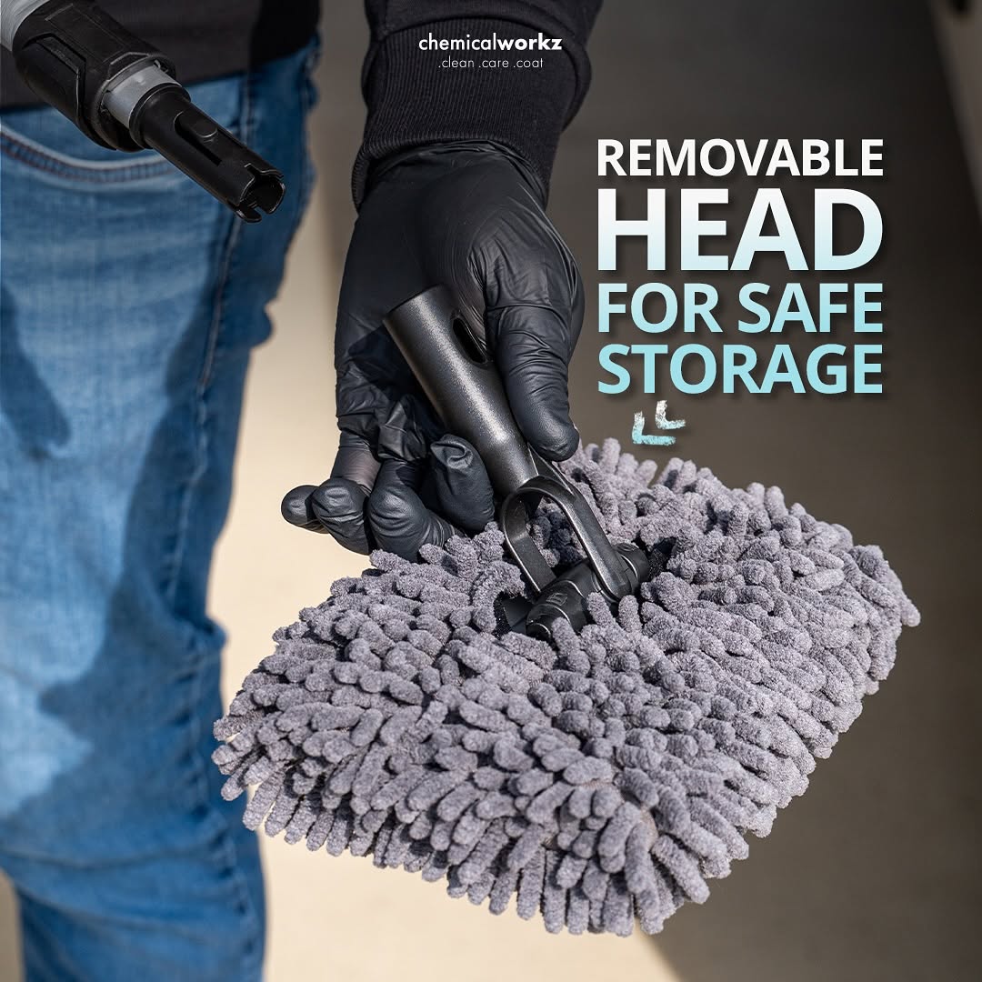 Person holding a cleaning tool with a removable head, wearing gloves, on a neutral background.