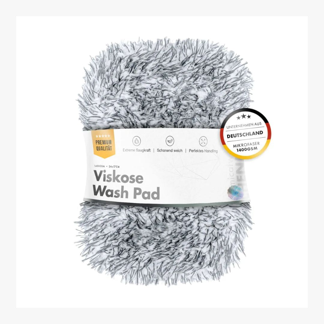 A fluffy gray and white shaggy Viskose Wash Pad with a white paper label band around it, photographed on a clean white background. A circular German quality badge is visible on the right side of the label.