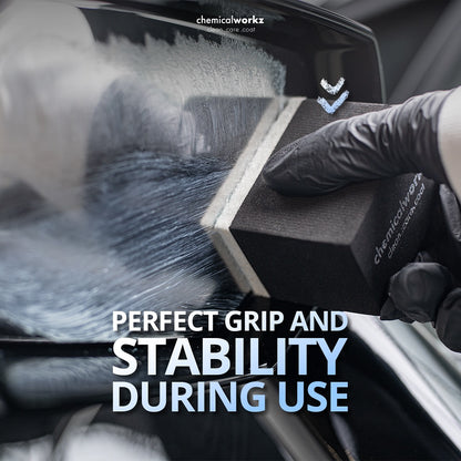 Person using a black tool with 'chemicalworkz' branding on a car window, emphasizing grip and stability.