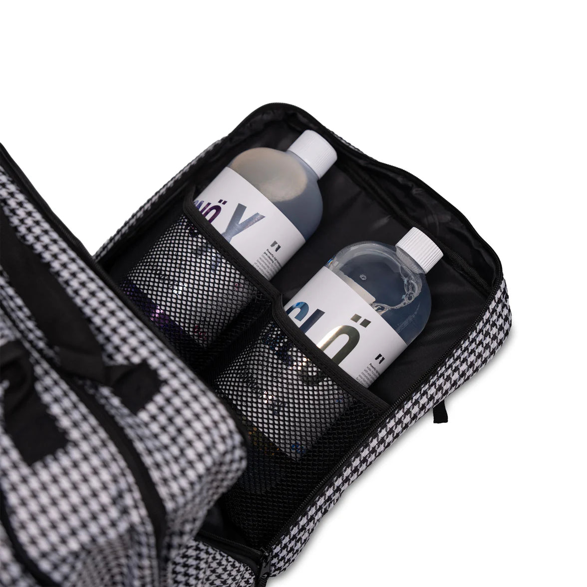 Black toiletry bag with mesh compartments containing bottles on a white background
