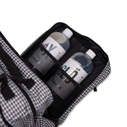 Black toiletry bag with mesh compartments containing bottles on a white background