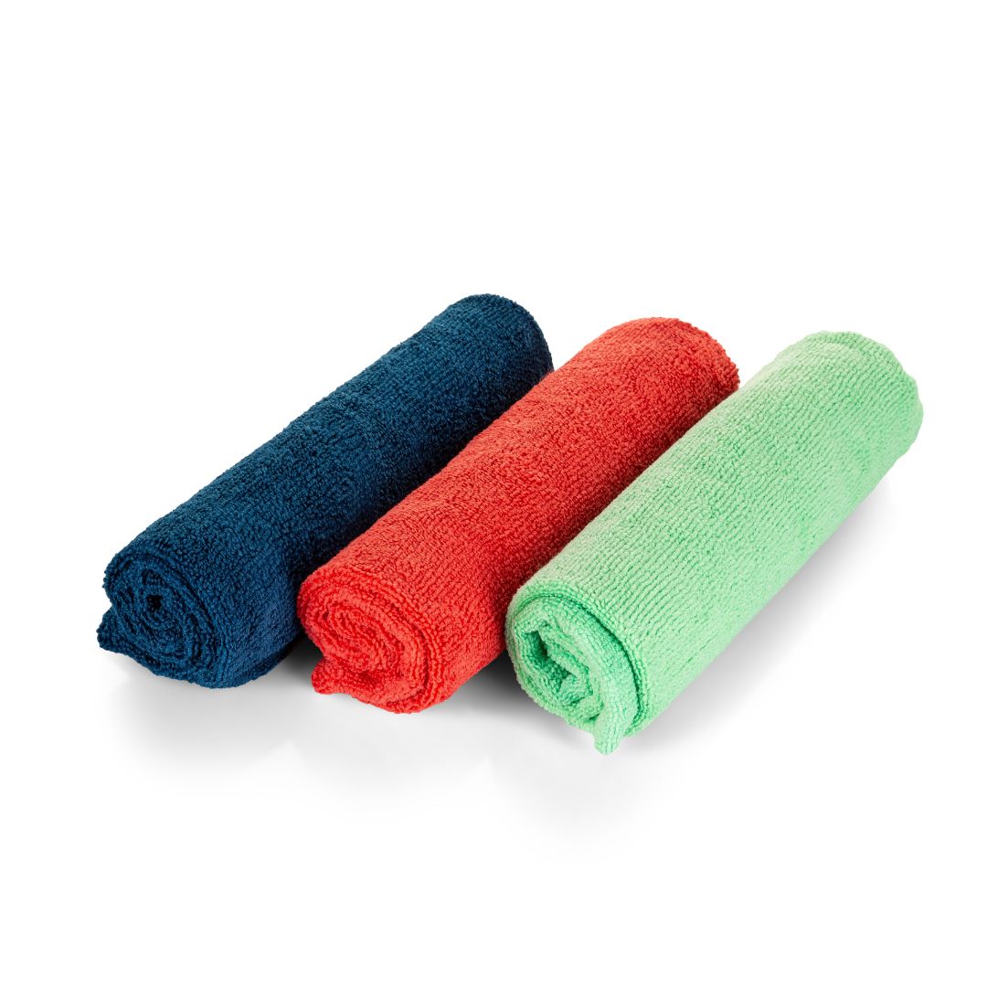 Three rolled-up towels in blue, red, and green on a white background