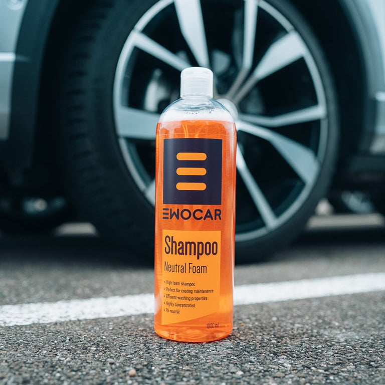 Bottle of Ewocar shampoo on a car's black rubber tire