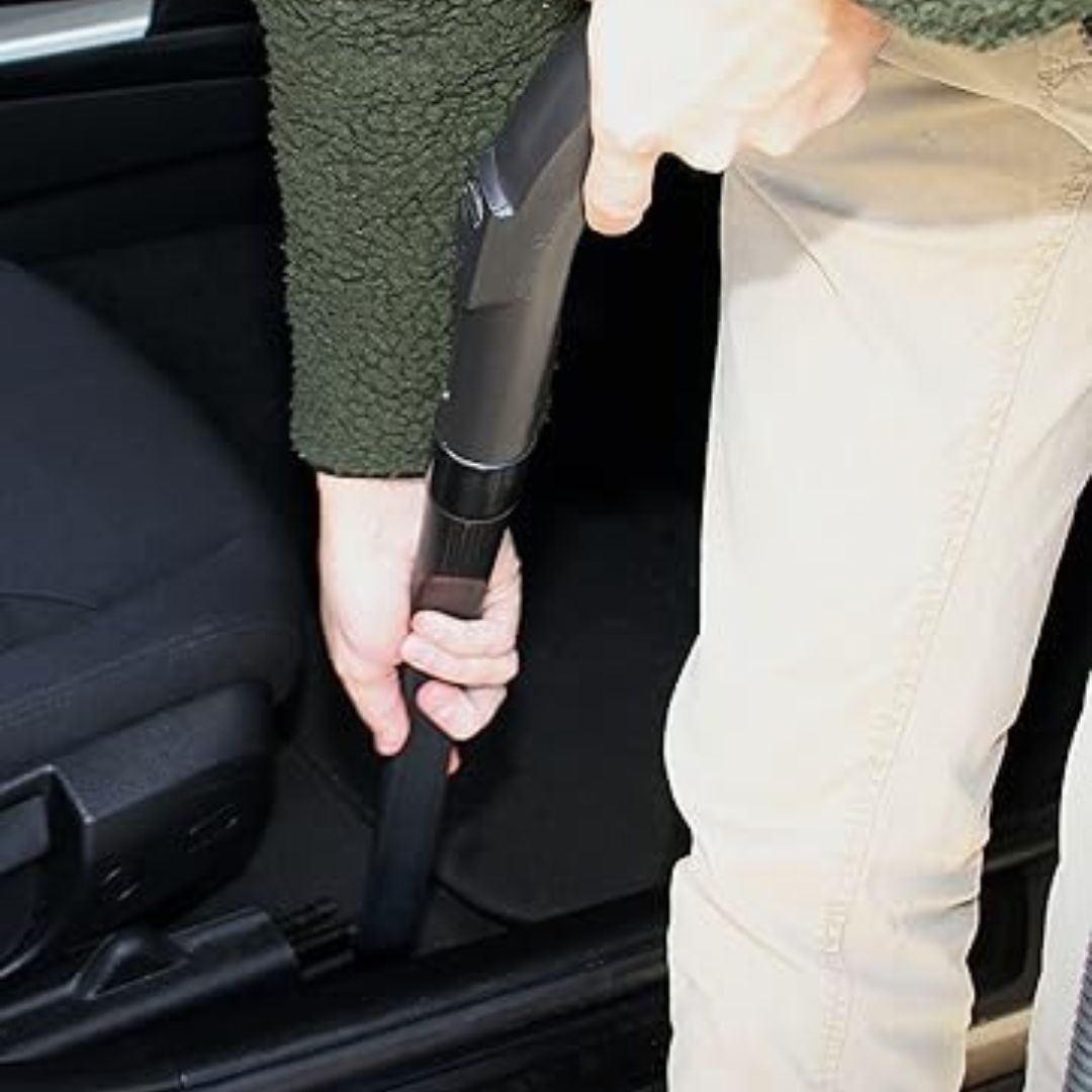 Person using a vacuum cleaner inside a car