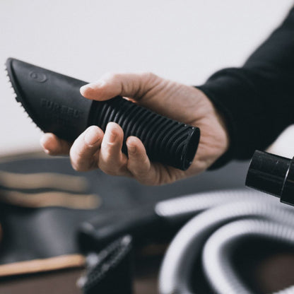 Hand holding a black Fur eel pet hair with 'fur eel' branding, blurred background