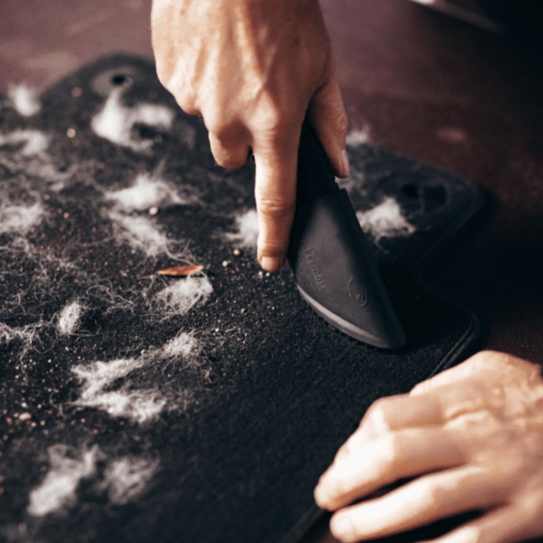 Person cleaning a Fur eel pet hair remover with a black cleaning tool