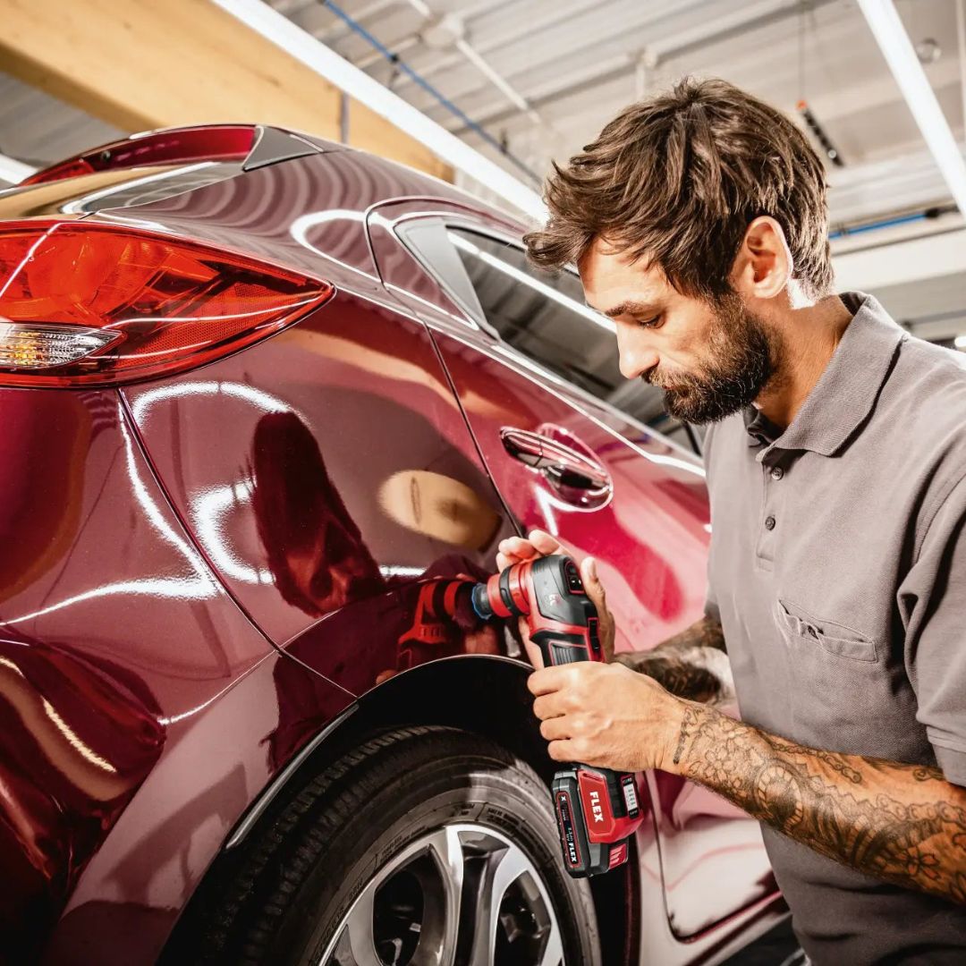 Person using a Flex PXE 80 on a red car in a garage setting