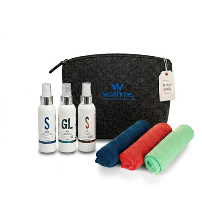 Washme travel care set featuring a black felt zippered pouch with the Washme logo, three white bottles with silver caps, and three rolled microfiber towels in blue, red, and green on a white background.