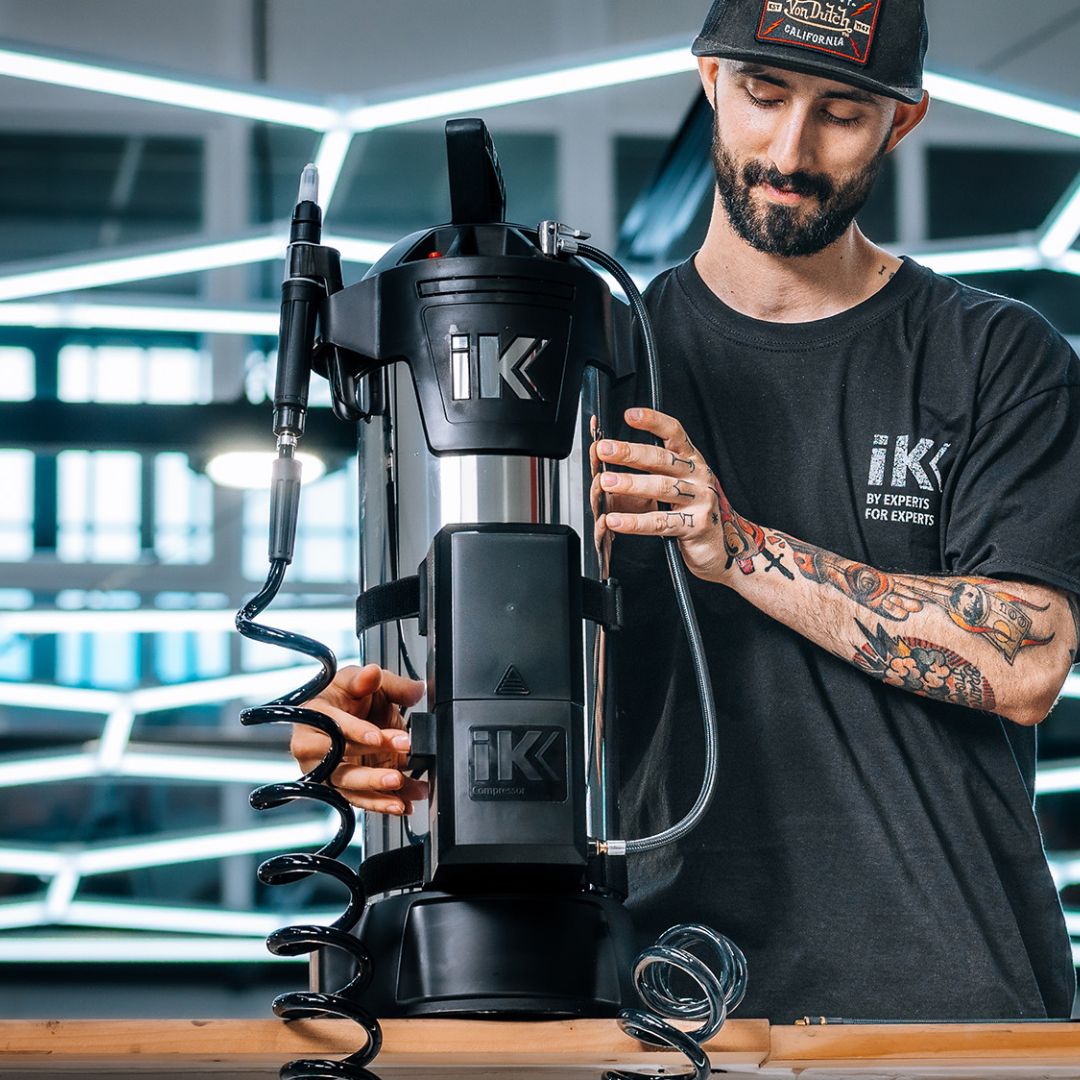 Person operating a IK Window Tinting and PPF Sprayer Stainless Steel 13L with hex light in the background