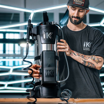 Person operating a IK Window Tinting and PPF Sprayer Stainless Steel 13L with hex light in the background