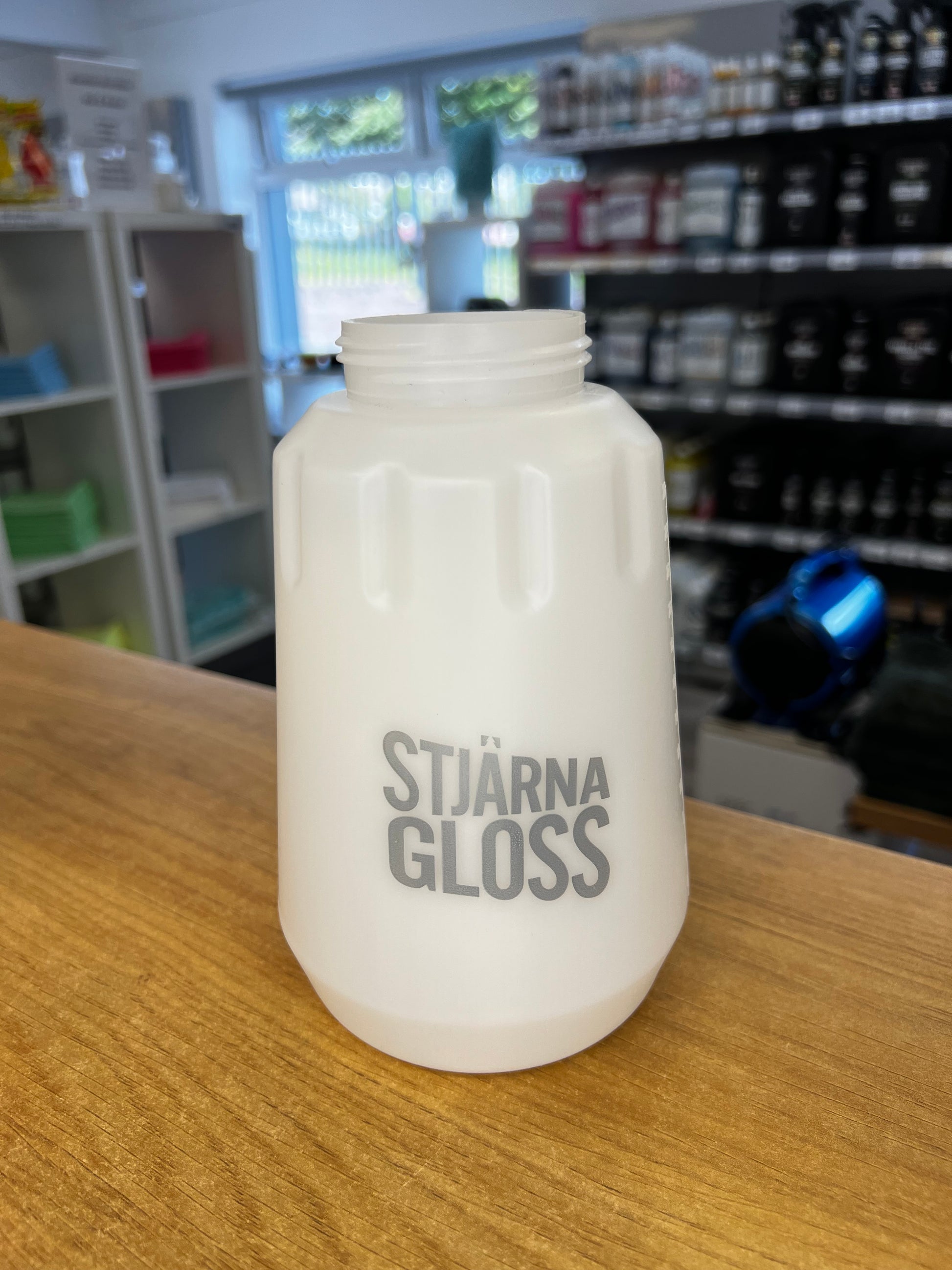 Stujarna Gloss bottle on a wooden surface with a blurred background