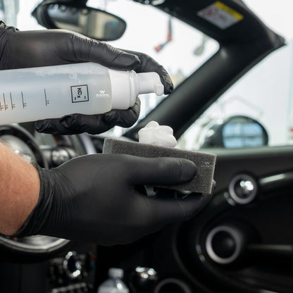Person using Koch Chemie The Finisher LeatherTexClean car interior with a spray bottle and sponge